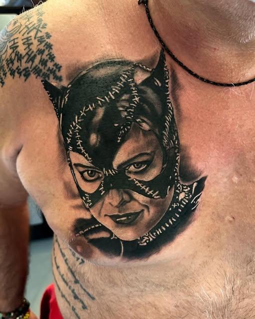 Black and grey portrait tattoo of Catwoman on a chest