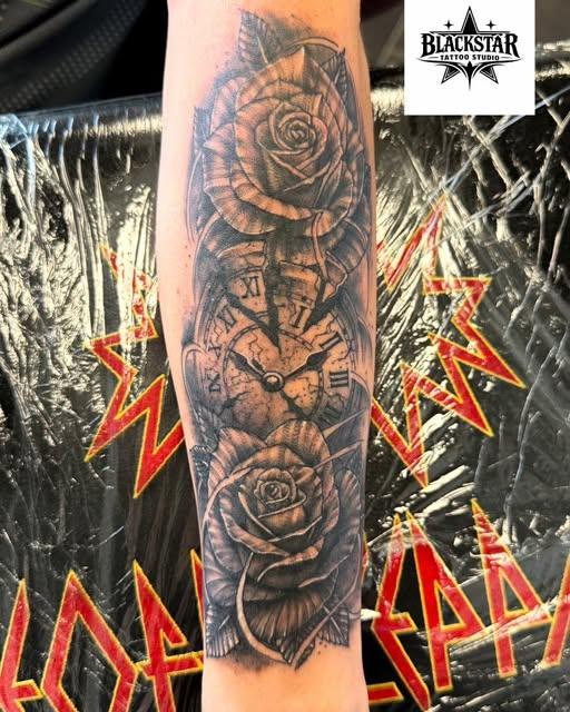 Black and grey forearm tattoo of roses framing a pocket watch